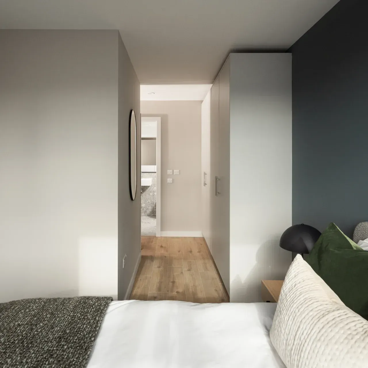 Modern bedroom with a bed, dark accent wall, white closet, and a doorway to a bright hall