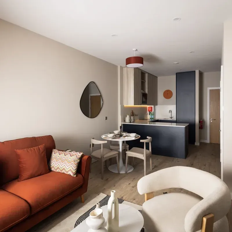 Modern open-plan living room with orange sofa, white chairs, and dark blue kitchen island