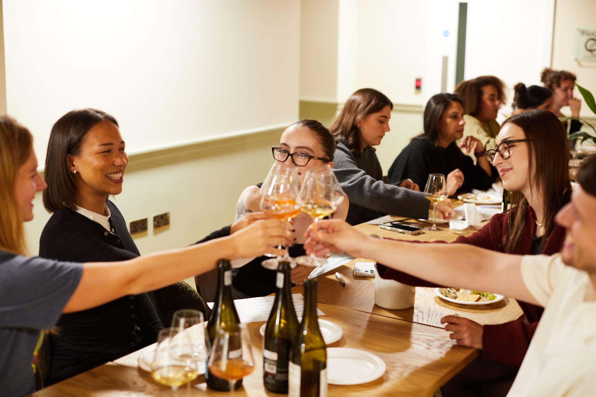 People toasting with wine glasses around a dining table in a bright restaurant