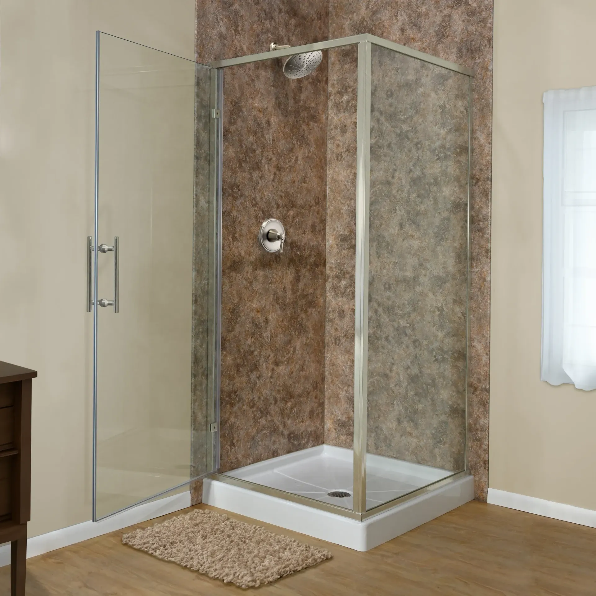 Corner shower with clear glass door, brown tile walls, and beige bath mat in a bathroom