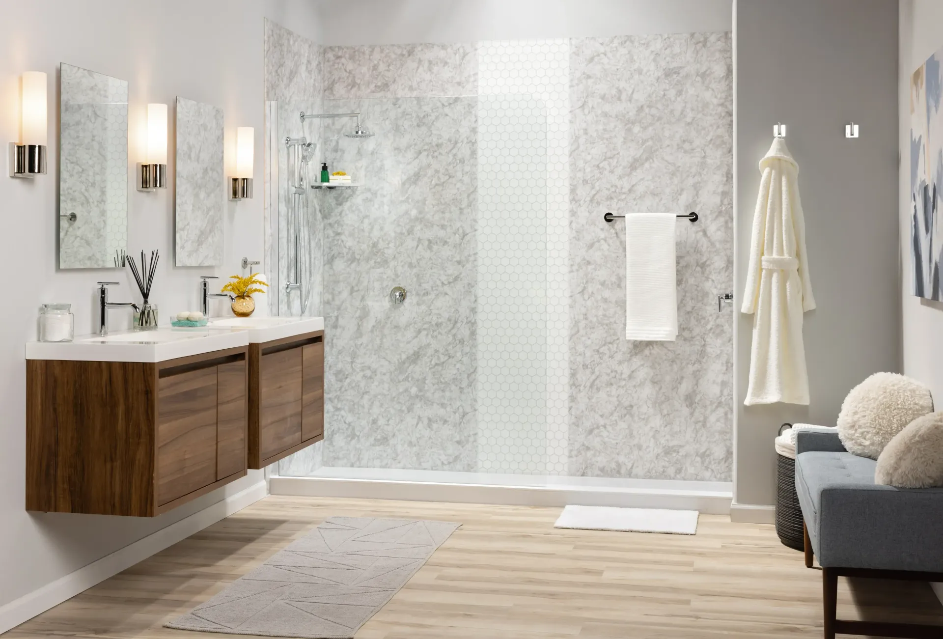 Modern bathroom with floating wood vanity, glass shower, white towels, and a small seating area.