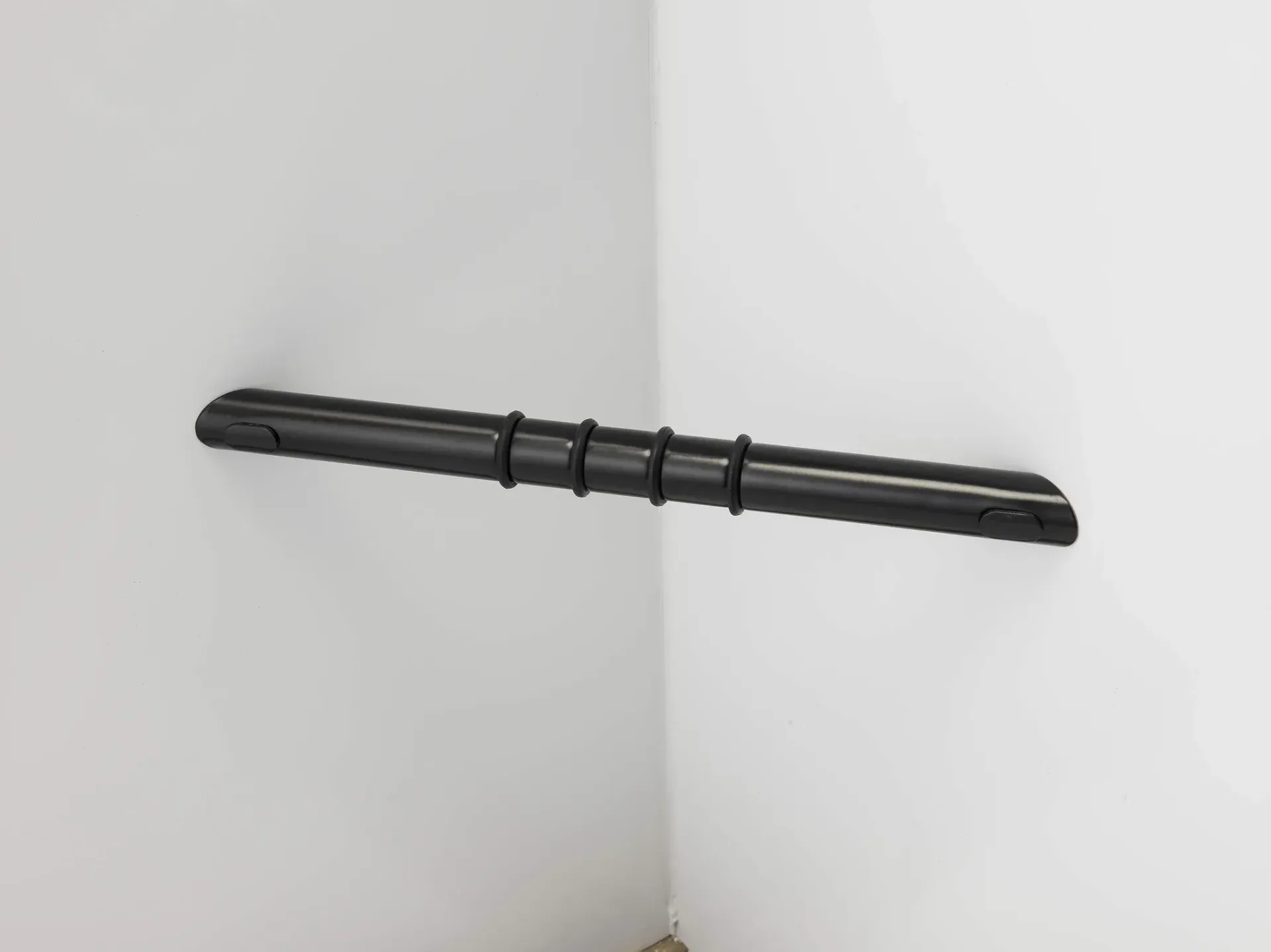 Black horizontal pipe or bar mounted on a white corner wall