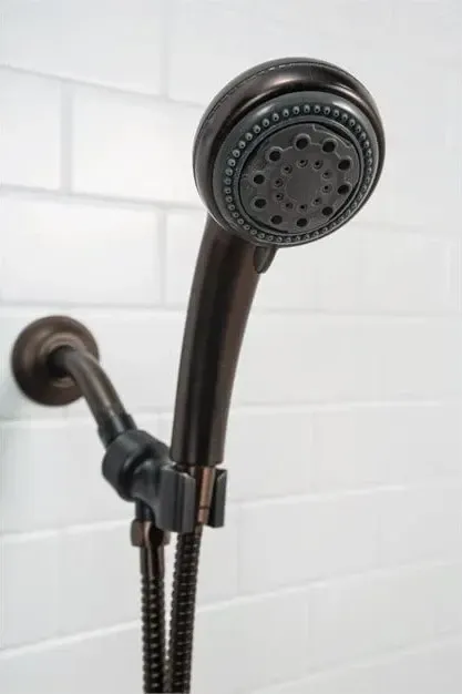 Black handheld shower head on a wall-mounted hose in a white tiled bathroom