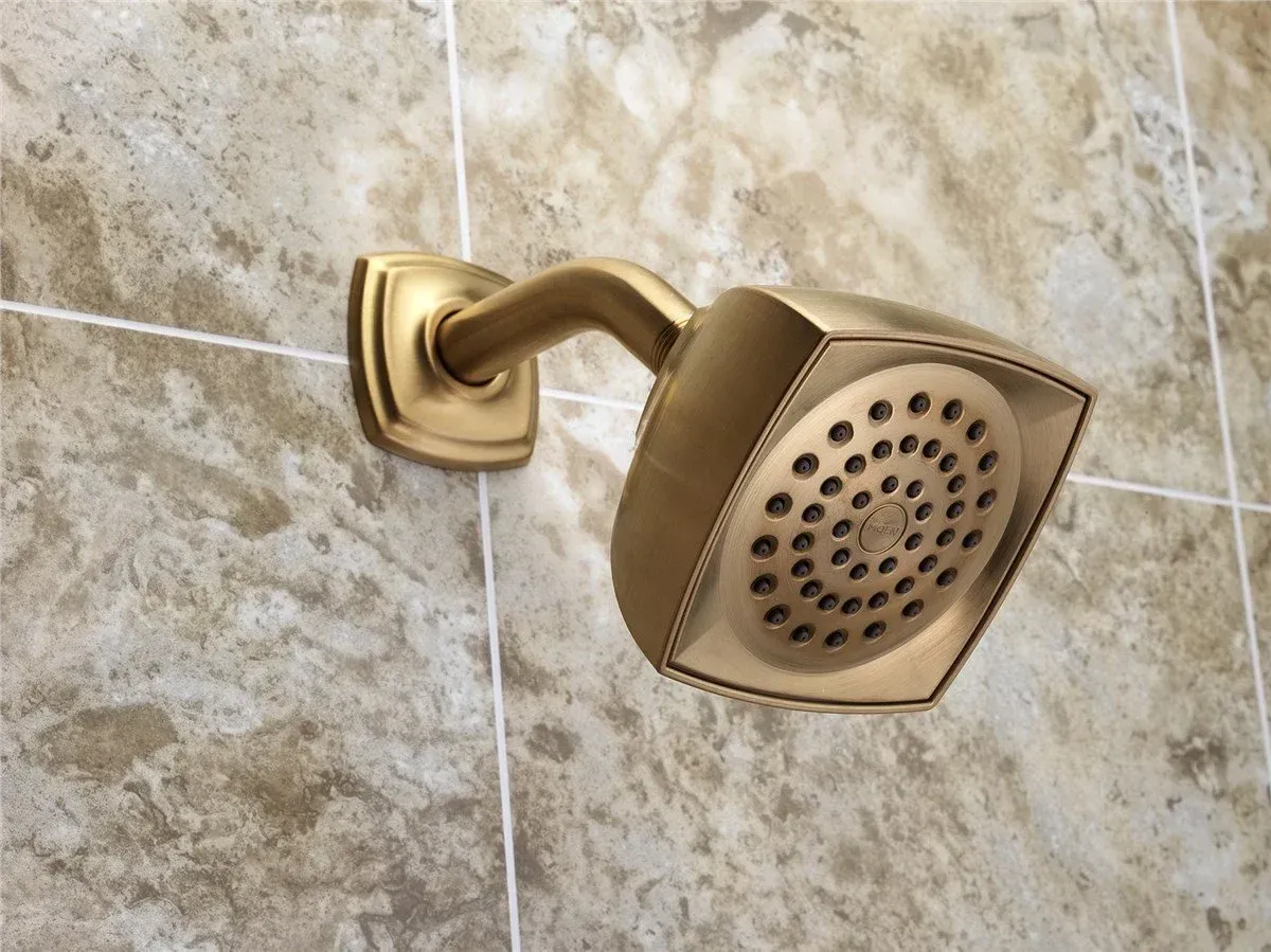 Gold showerhead mounted on a beige tiled bathroom wall