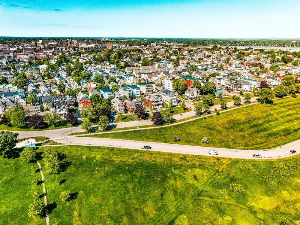 Aerial view of a suburban neighborhood beside green fields under a clear blue sky