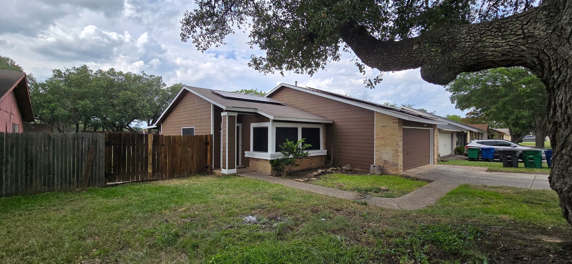 Black metal roof on a red brick house with a blue sky background.