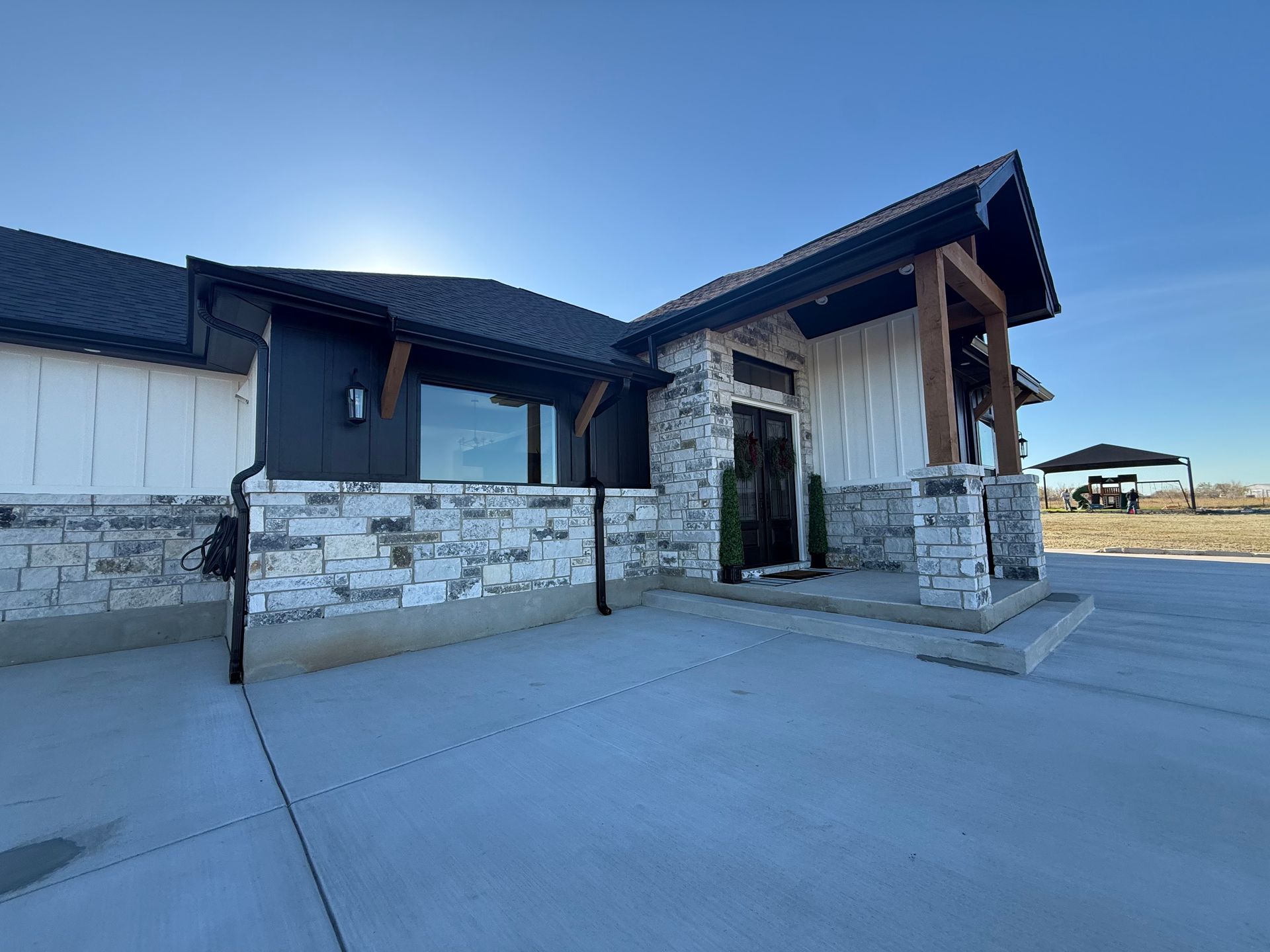 Black metal roof on a red brick house with a blue sky background.