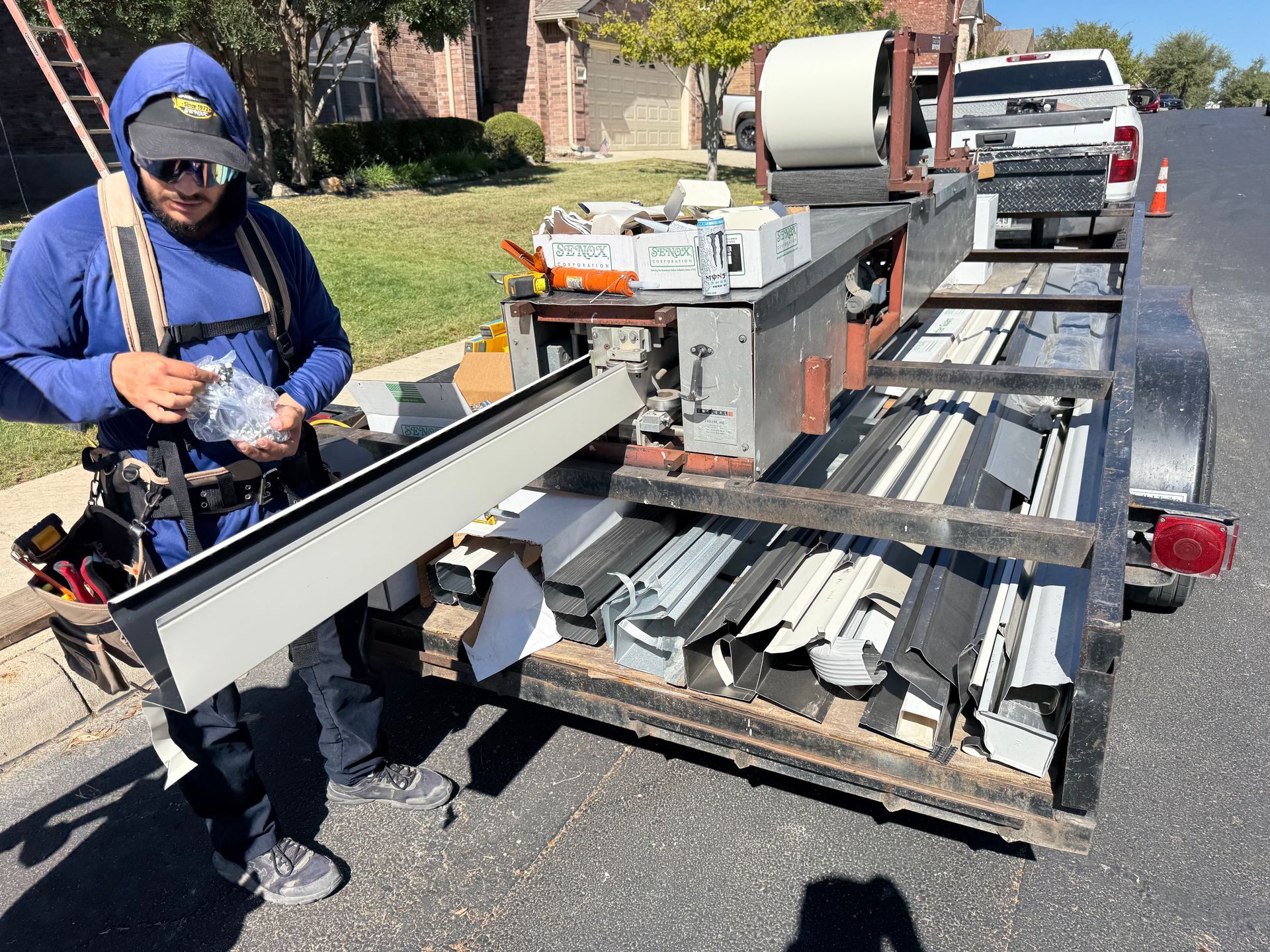 Man with tools near trailer filled with building materials on a street.