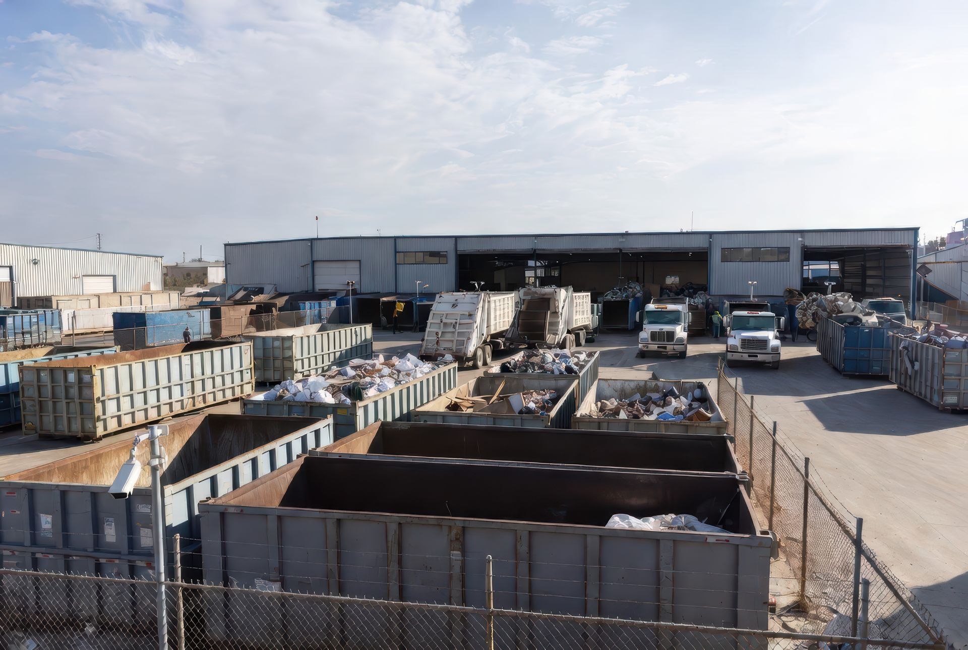 Commercial scrap metal recycling facility with industrial containers and trucks at a metal yard in o