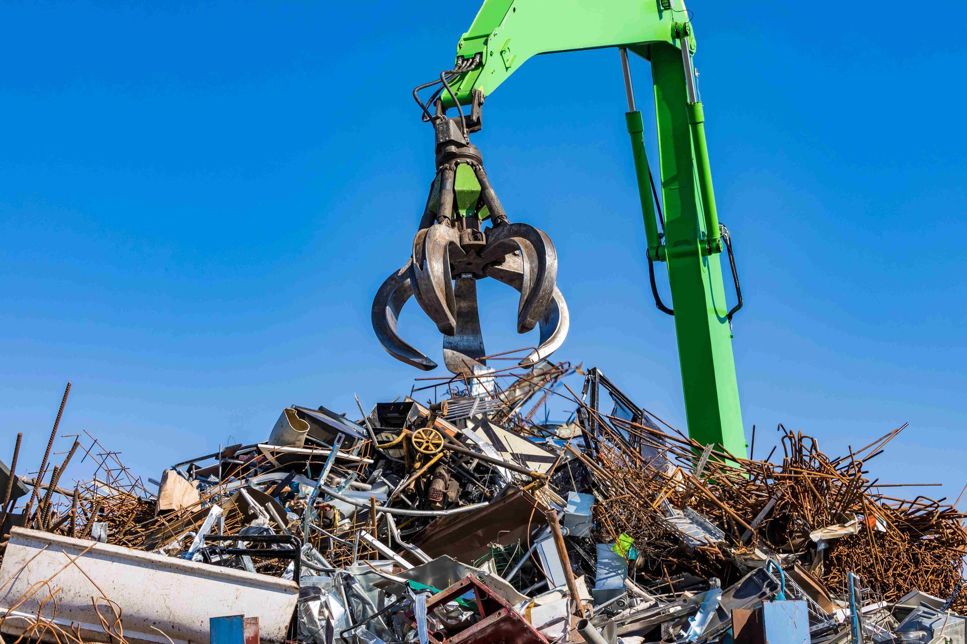 Crane grapple claw lifting scrap metal at a scrap metal recycling yard. Crane grapple claw lifting scrap metal at a scrap metal recycling yard.