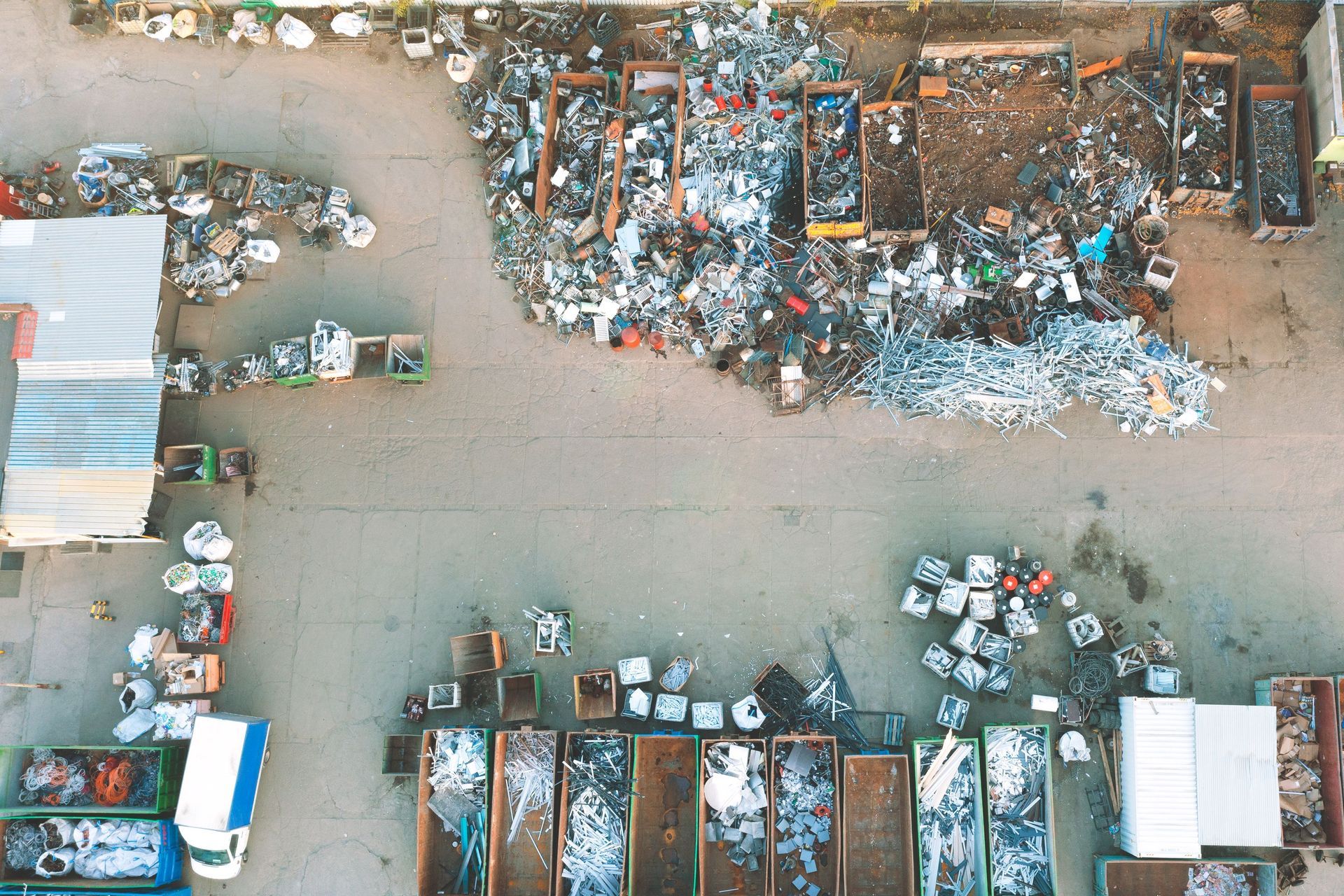 Overhead view of scrap metal piles sorted in bins at an industrial recycling yard. Overhead view of scrap metal piles sorted in bins at an industrial recycling yard.