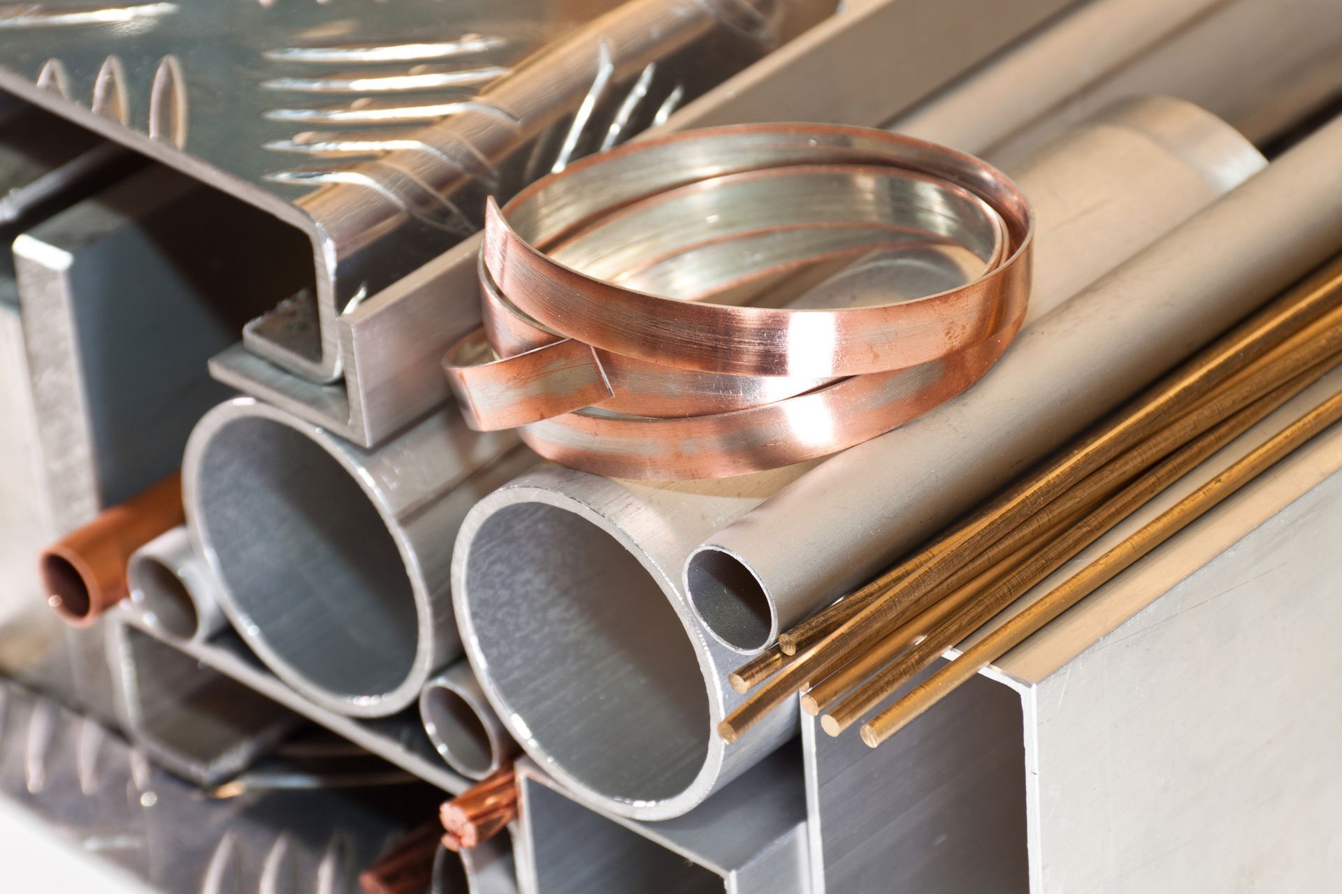 Assorted metal tubes, bars, and a copper band; various shapes, sizes, and colors of metal materials.