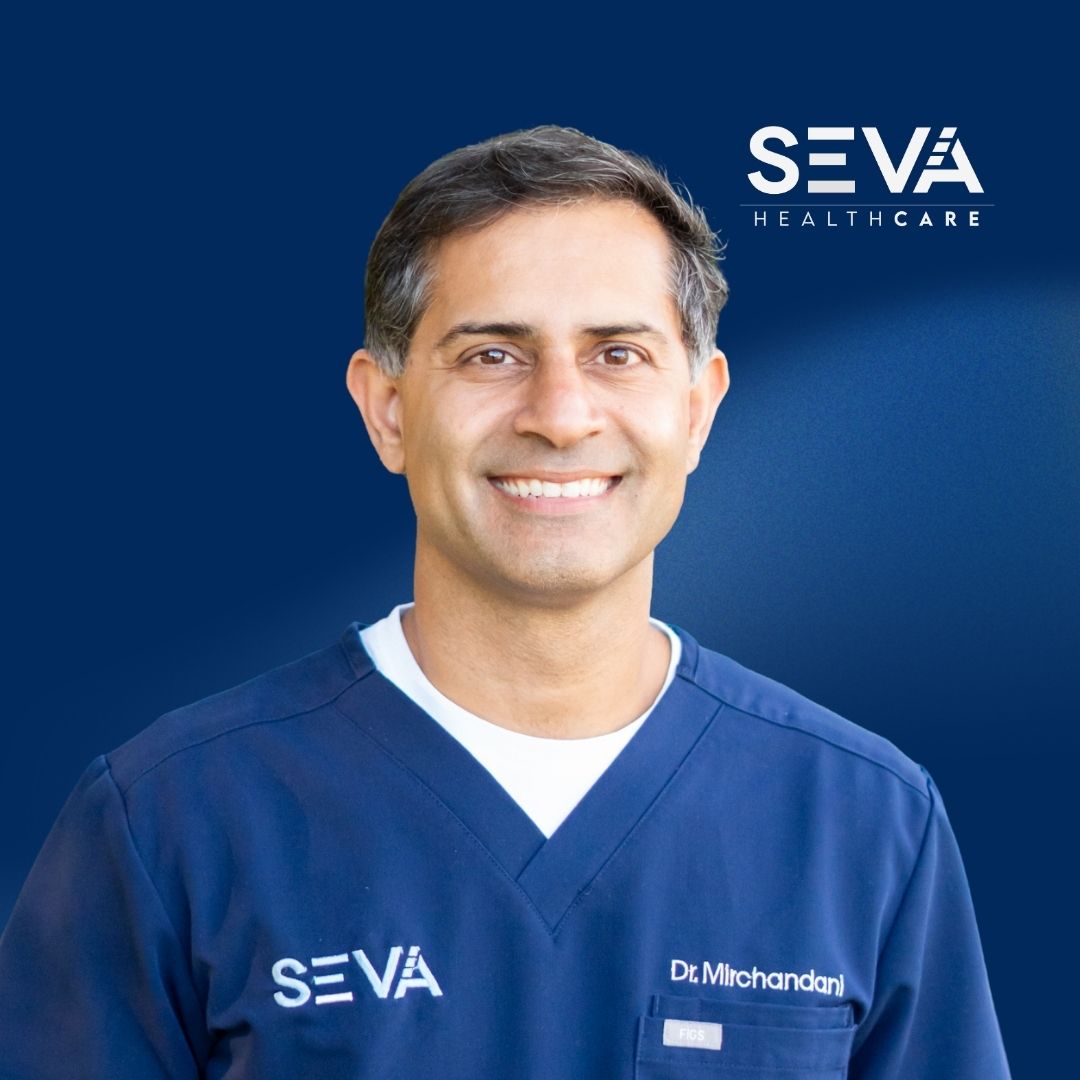 Portrait of a smiling SEVA Healthcare staff member in blue scrubs against a blue background