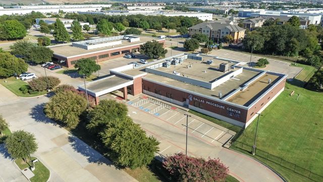 Aerial view of a school campus with brick buildings, tennis courts, trees, and parking lots