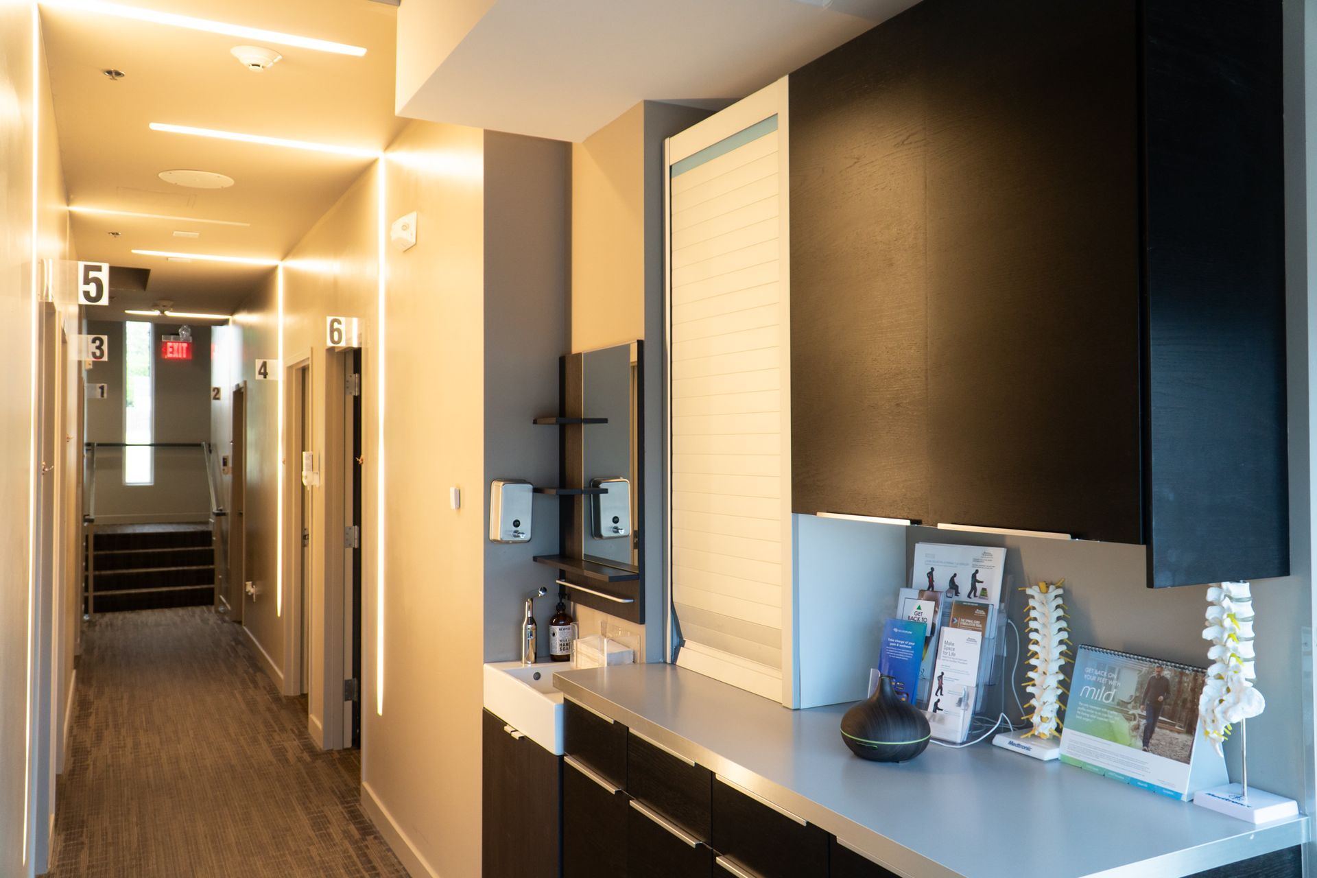 Modern apartment hallway with warm lighting, black cabinetry, and a console table by the wall
