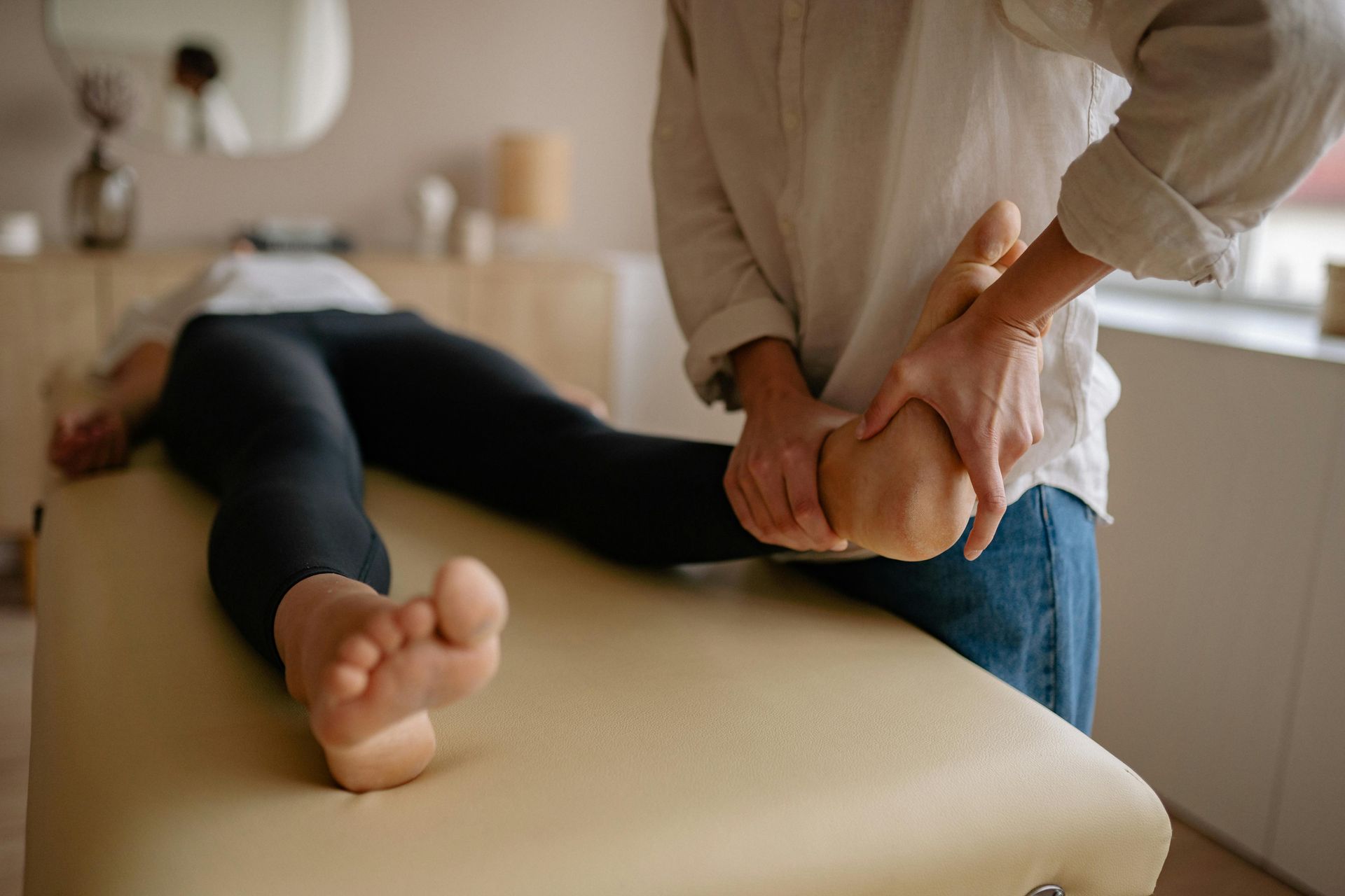 Massage therapist stretching a client's arm on a treatment table in a spa room