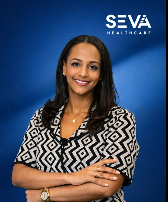 Smiling woman with folded arms in patterned blouse against a blue SEVA Healthcare backdrop