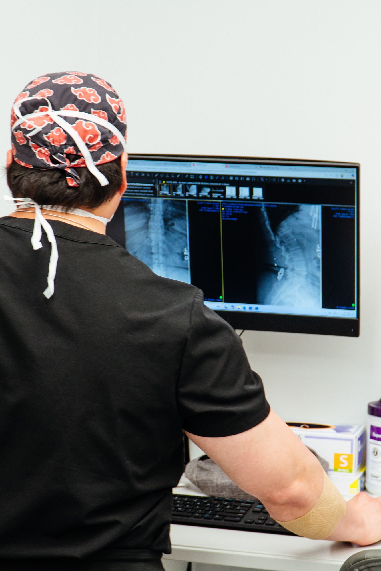 Doctor reviewing X-ray images on a computer in a clinic office.