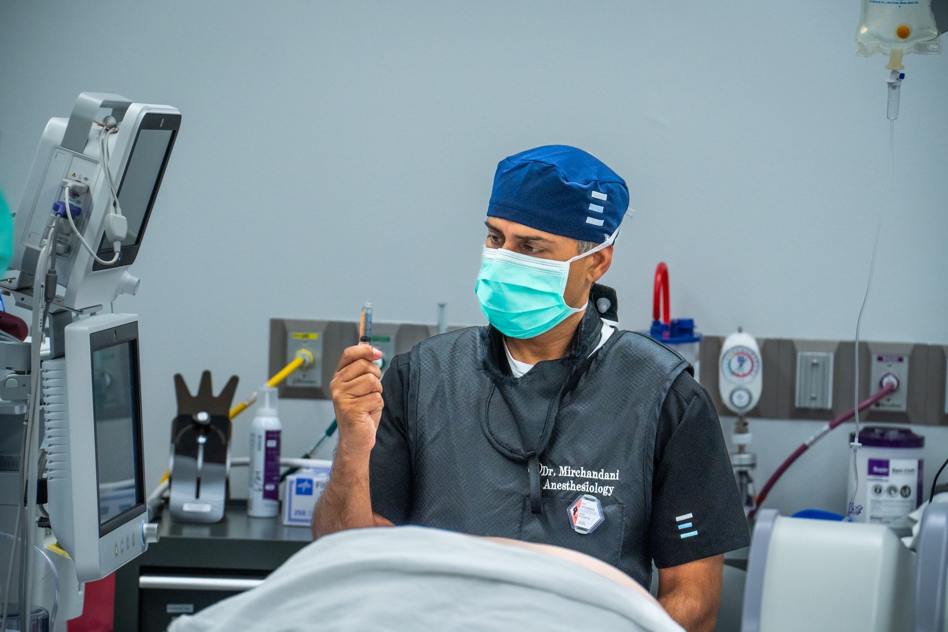 Dentist in blue cap and mask holding a dental tool in a clinic chair