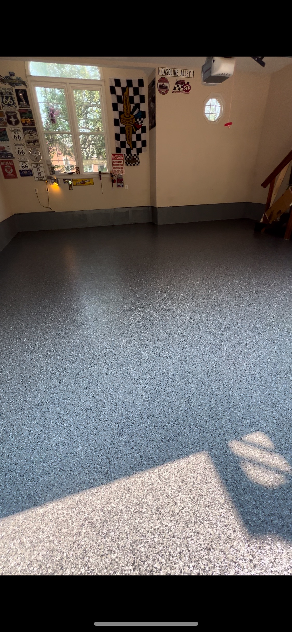 Empty room with patterned floor, window, and wall decor. Sunlight creates shadows across the floor.