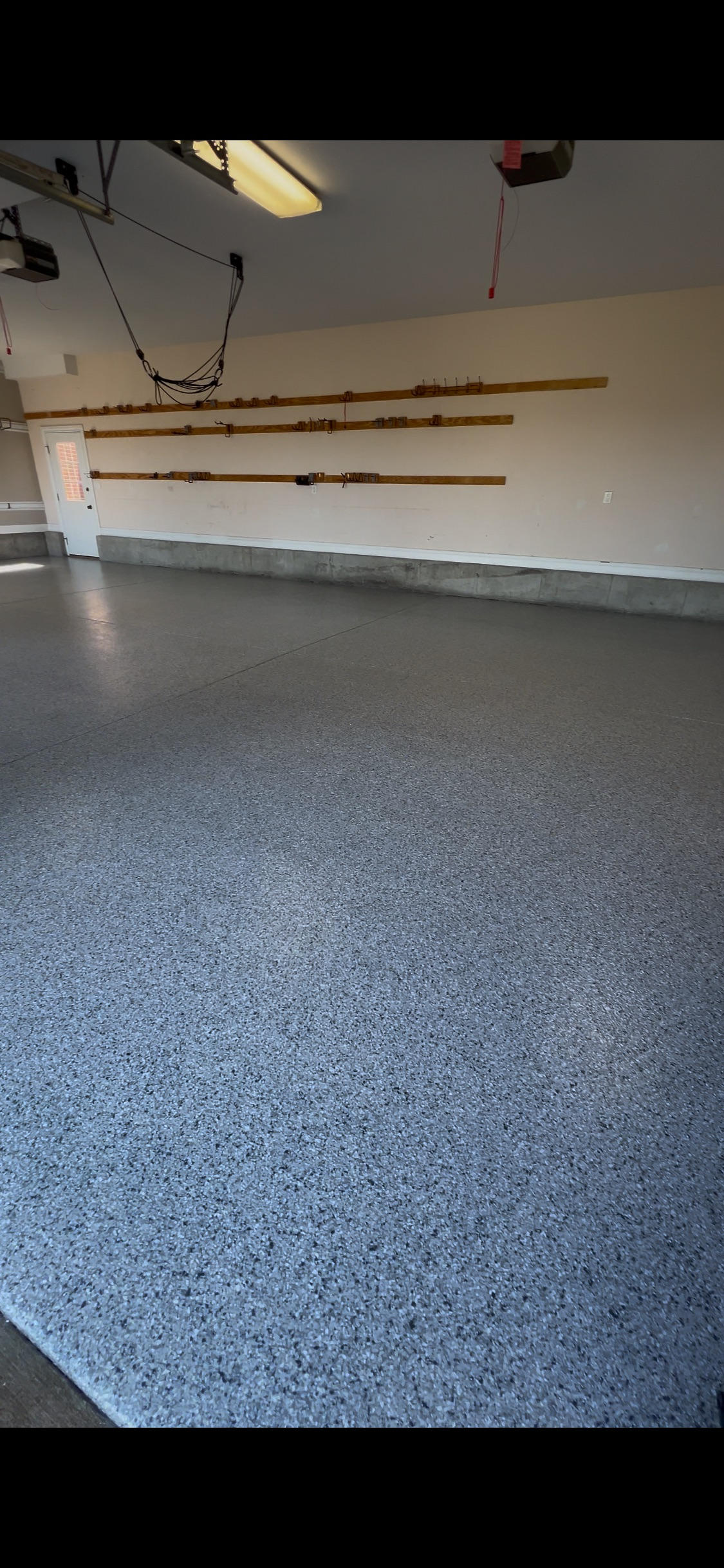 Empty garage with a speckled epoxy floor and wall-mounted storage racks.