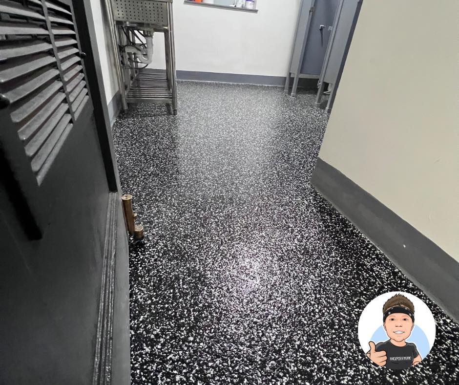 Hallway with black and white speckled floor, gray walls, and open door.