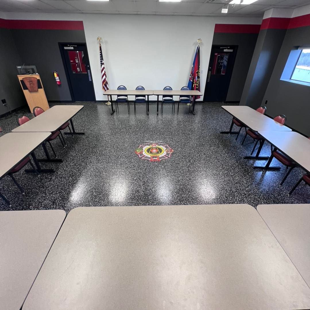 Conference room with tables in a U-shape around a central floor design, with flags, doors, and a neutral wall.