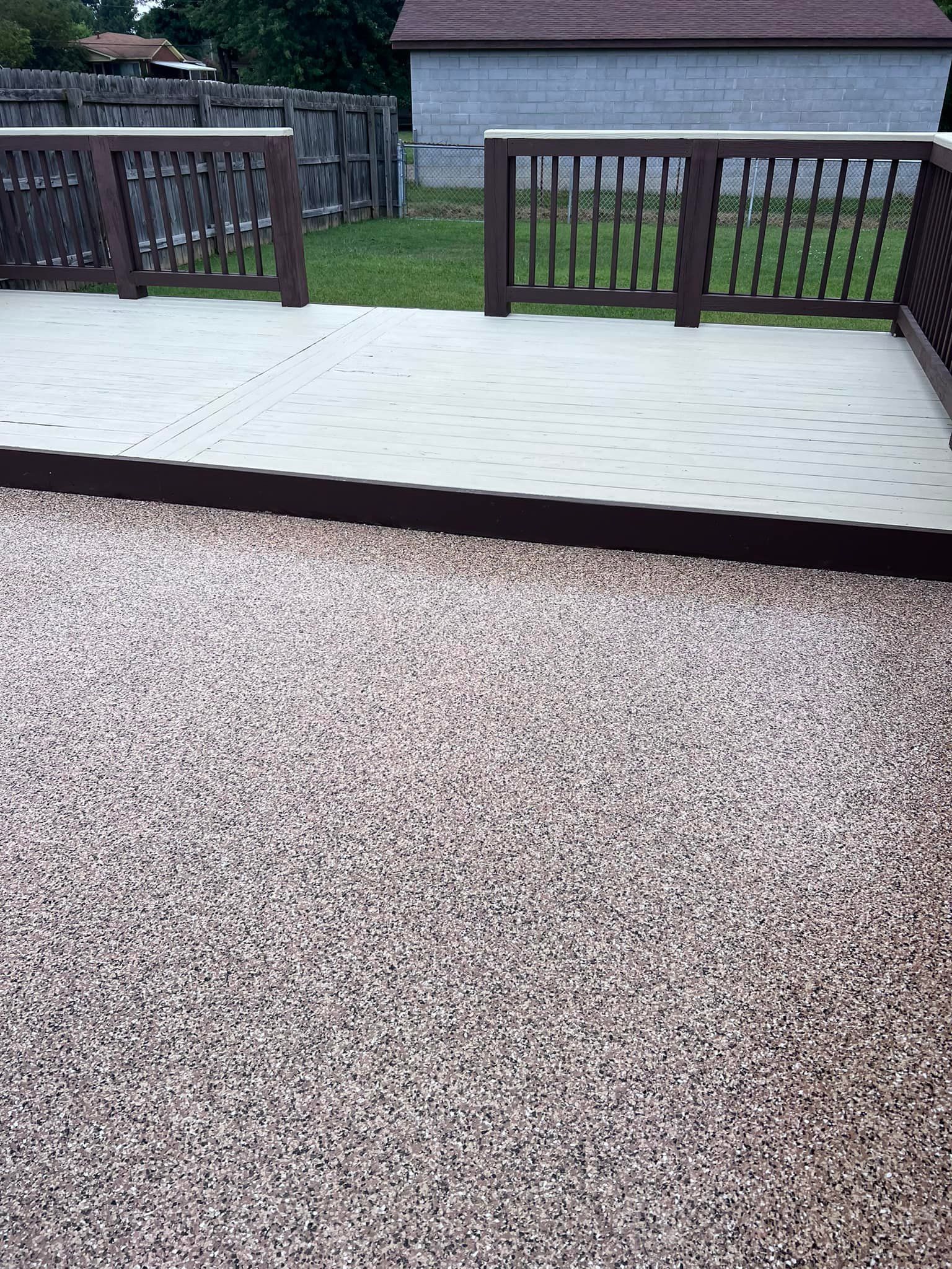 A deck with brown railing, leading to a gravel area.