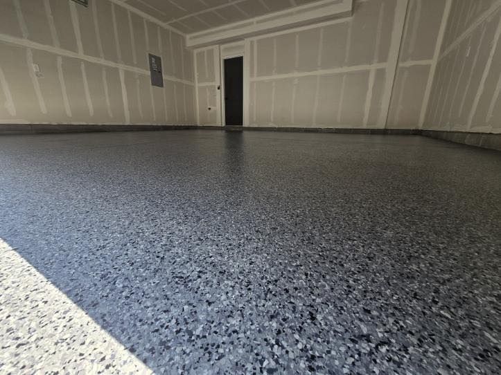 Garage interior with a shiny, speckled epoxy floor. Walls are unfinished drywall.