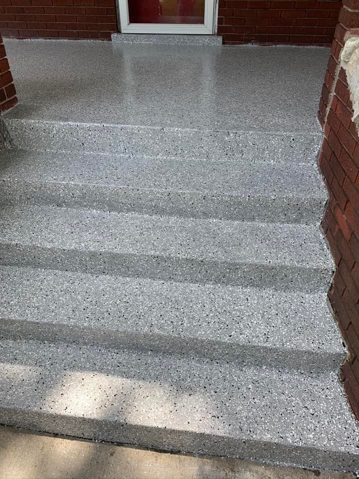 Gray terrazzo front steps leading to a red-framed door.