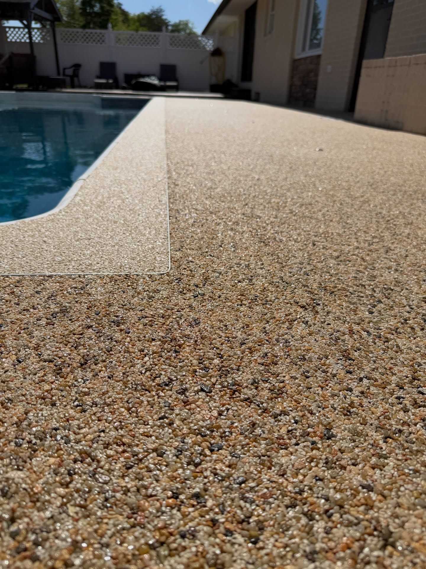 Textured poolside ledge beside a swimming pool in bright sunlight