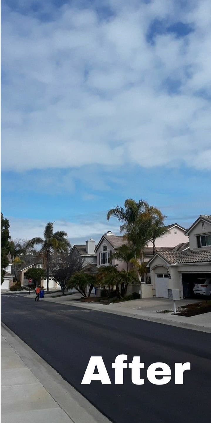 Suburban street with houses and palm trees under a partly cloudy sky.