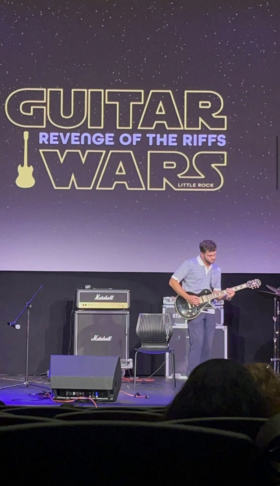 A man playing guitar on stage during the Guitar Wars event.