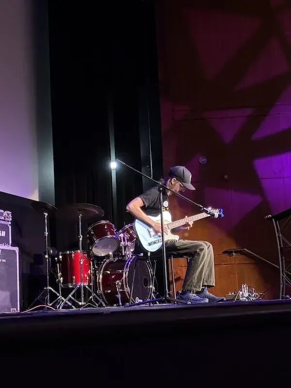 A man playing guitar while competing on stage in the Guitar Wars Event.
