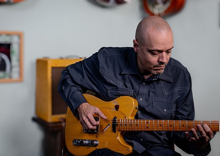 Instructor David Dunavant playing the guitar in his studio.
