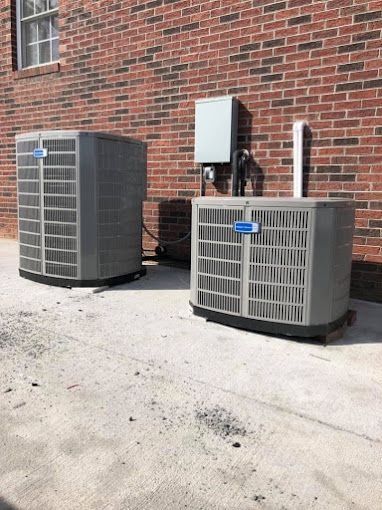 Two air conditioners are sitting outside of a brick building.
