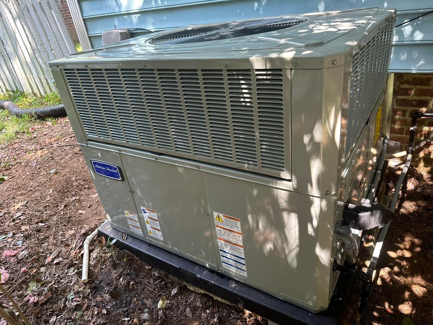 A large air conditioner is sitting outside of a house.