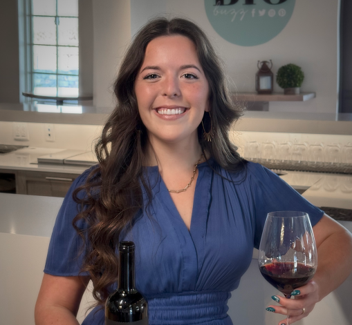 A girl in a blue dress is holding a glass of wine