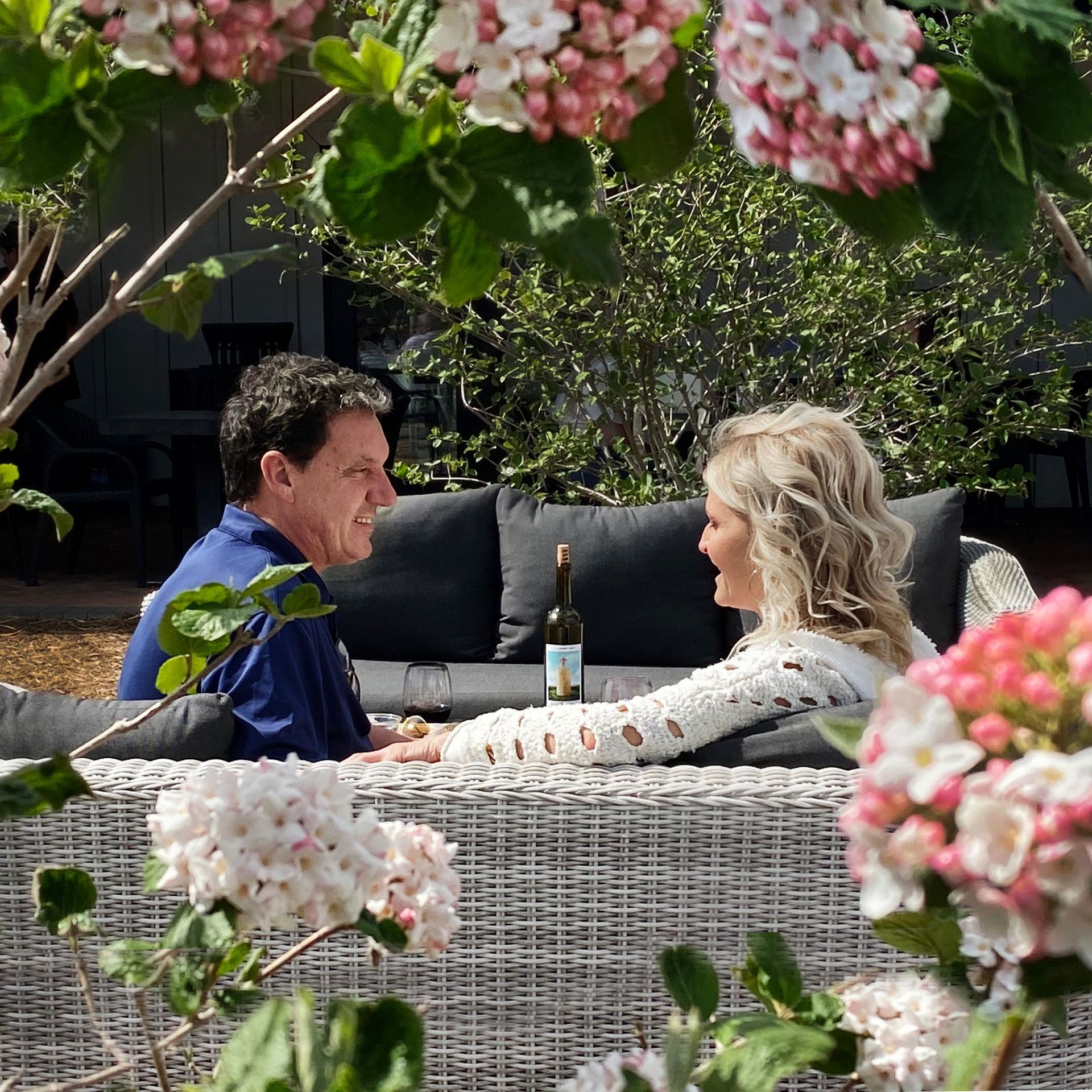 A man and a woman are sitting on a couch drinking wine