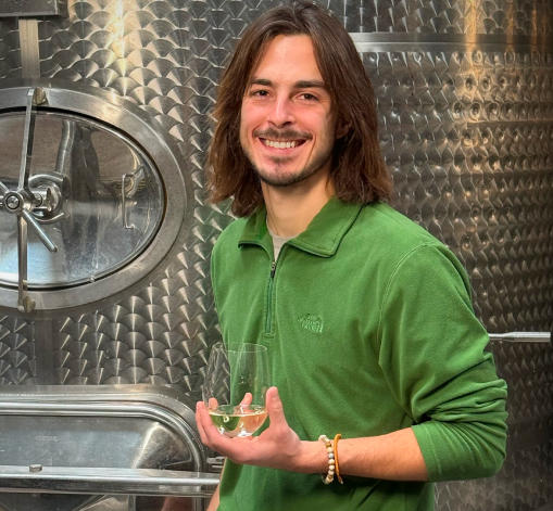 A woman in a blue sweater is holding a bottle of wine.