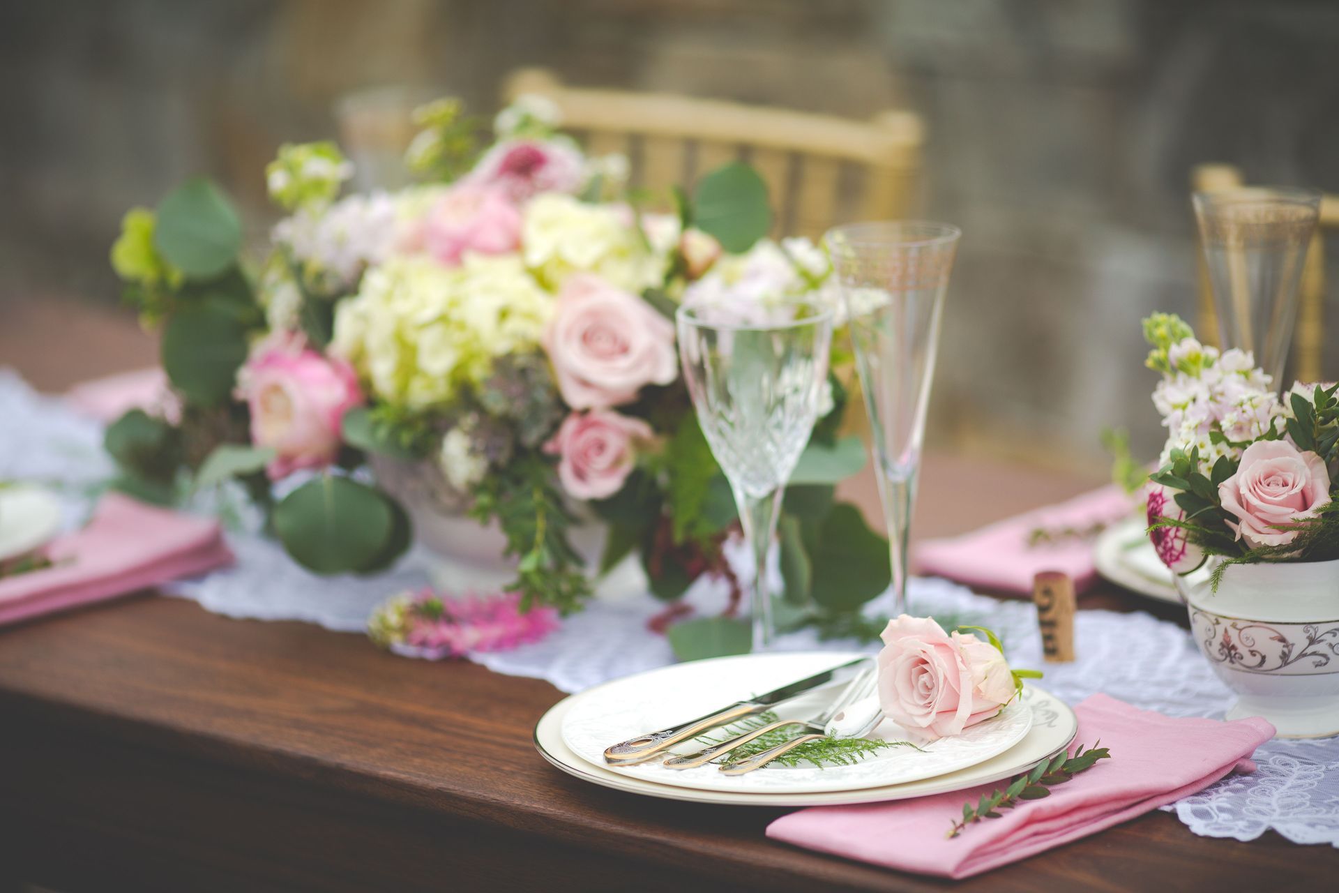 A table with plates , utensils , glasses , and flowers on it.
