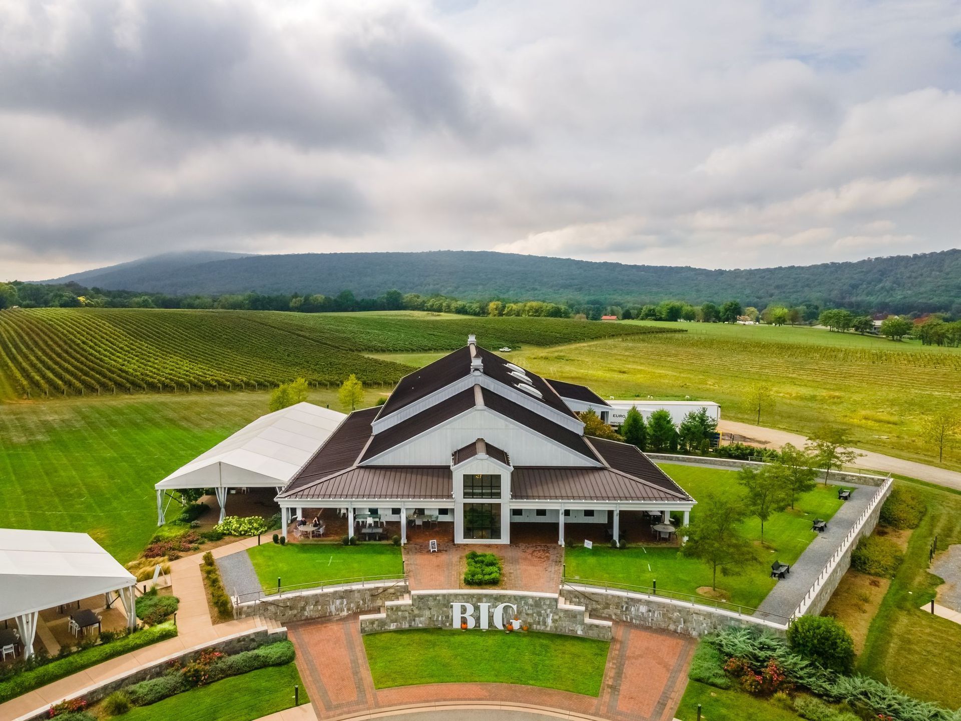 An aerial view of a large white building in the middle of a vineyard.