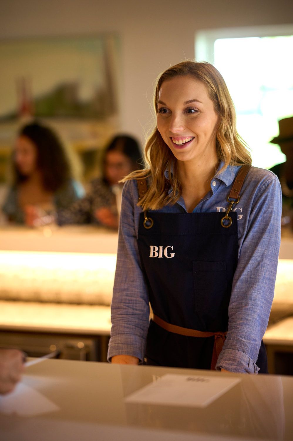 A woman in an apron is standing at a counter in a restaurant.