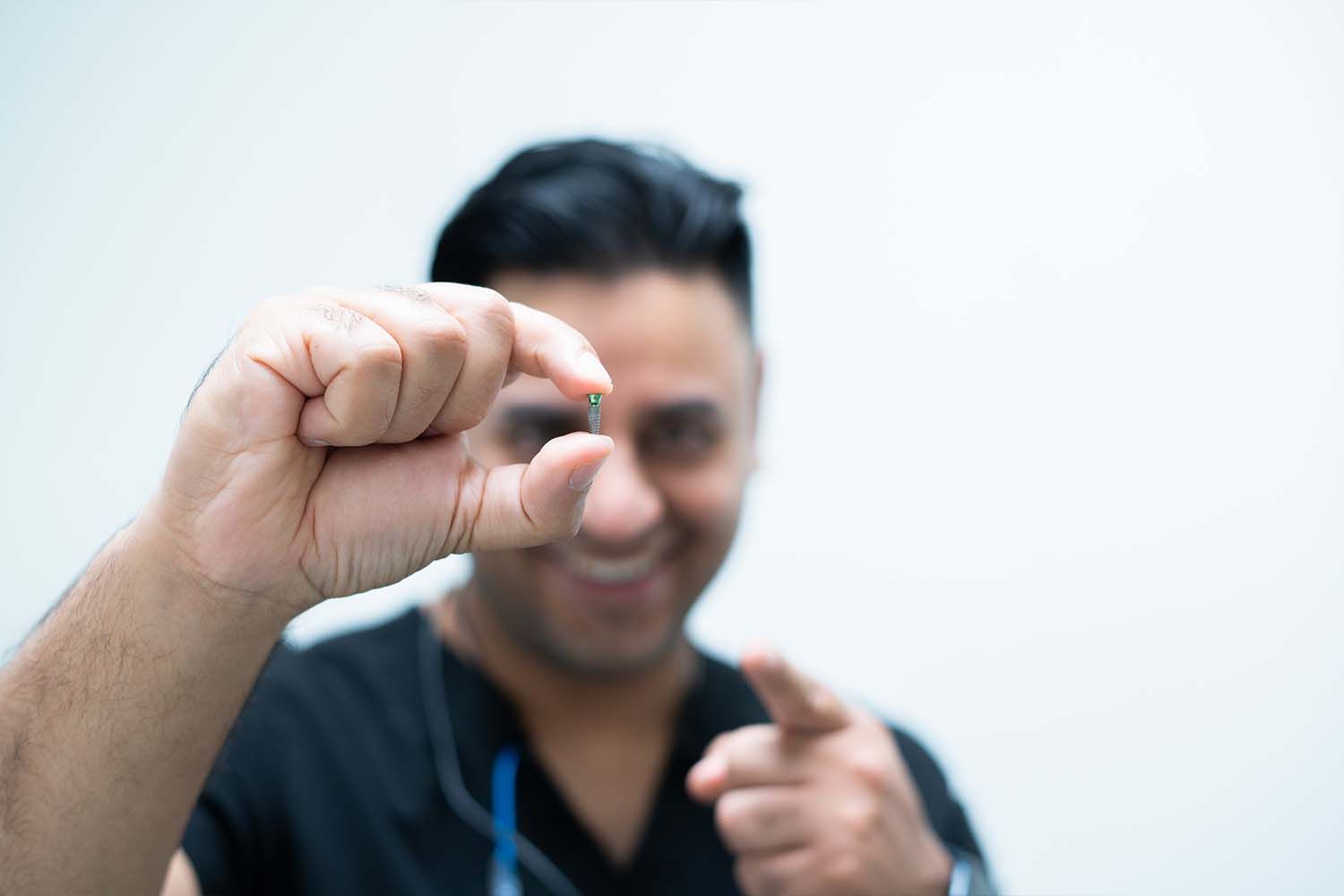A dentist is holding a model of teeth and a pen.