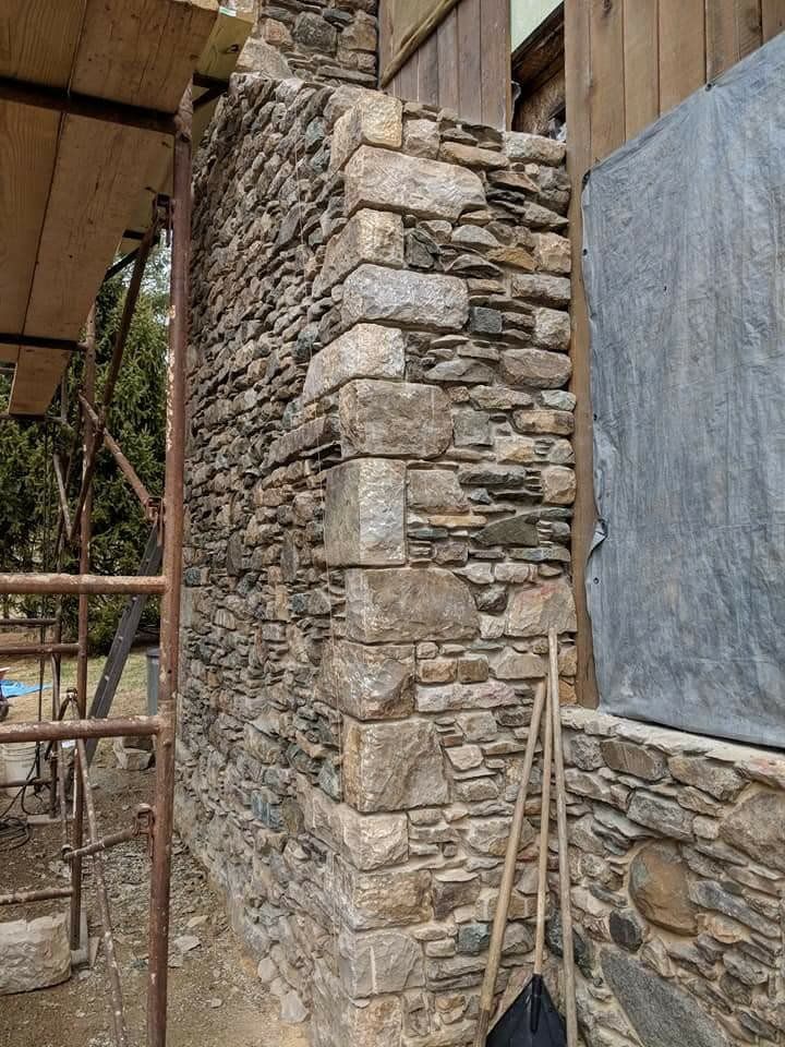 Stone column at a building under construction, with scaffolding and a blue tarp covering part of the wall.