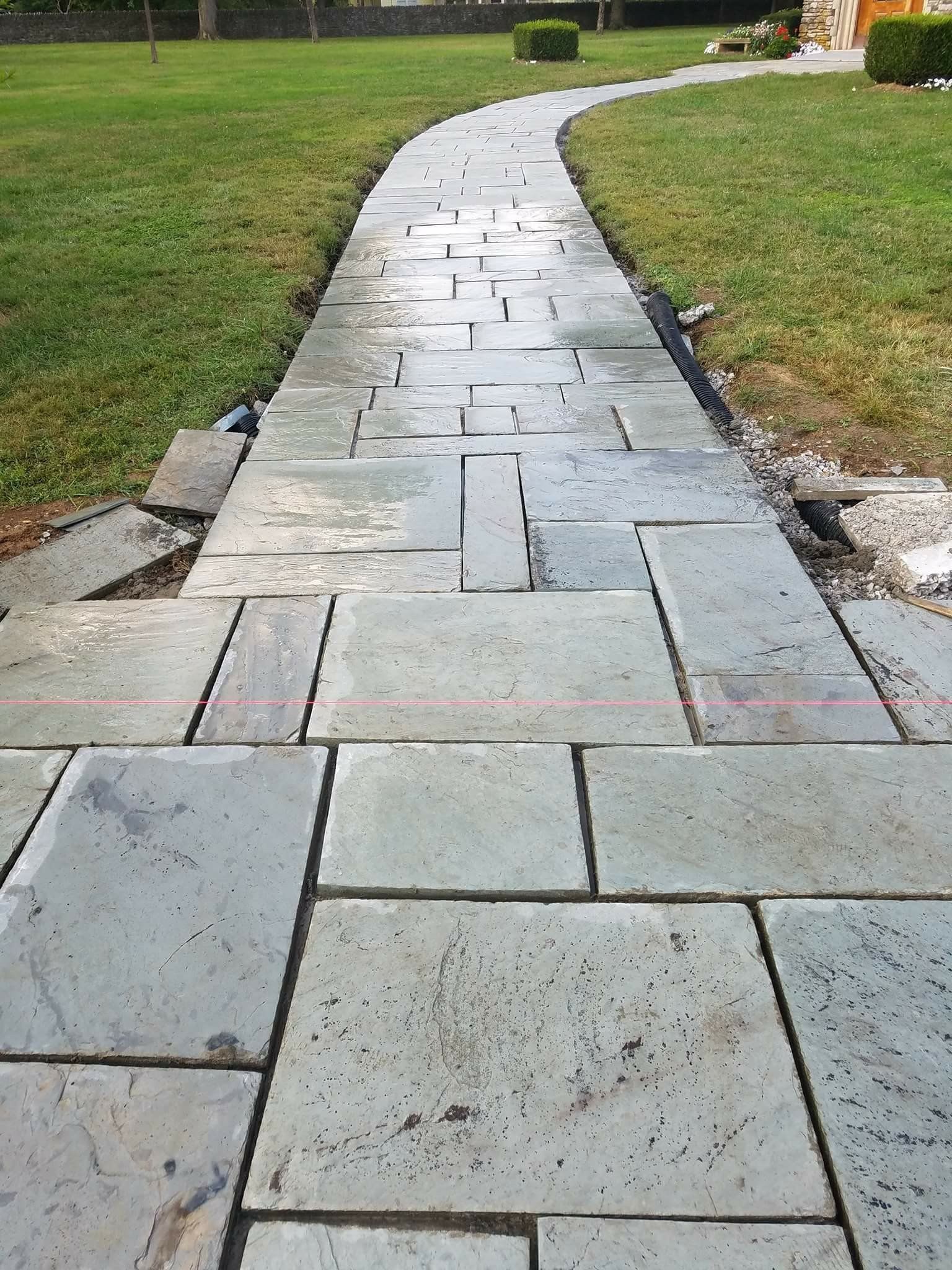 Curved stone walkway through a grassy park, leading into the distance.