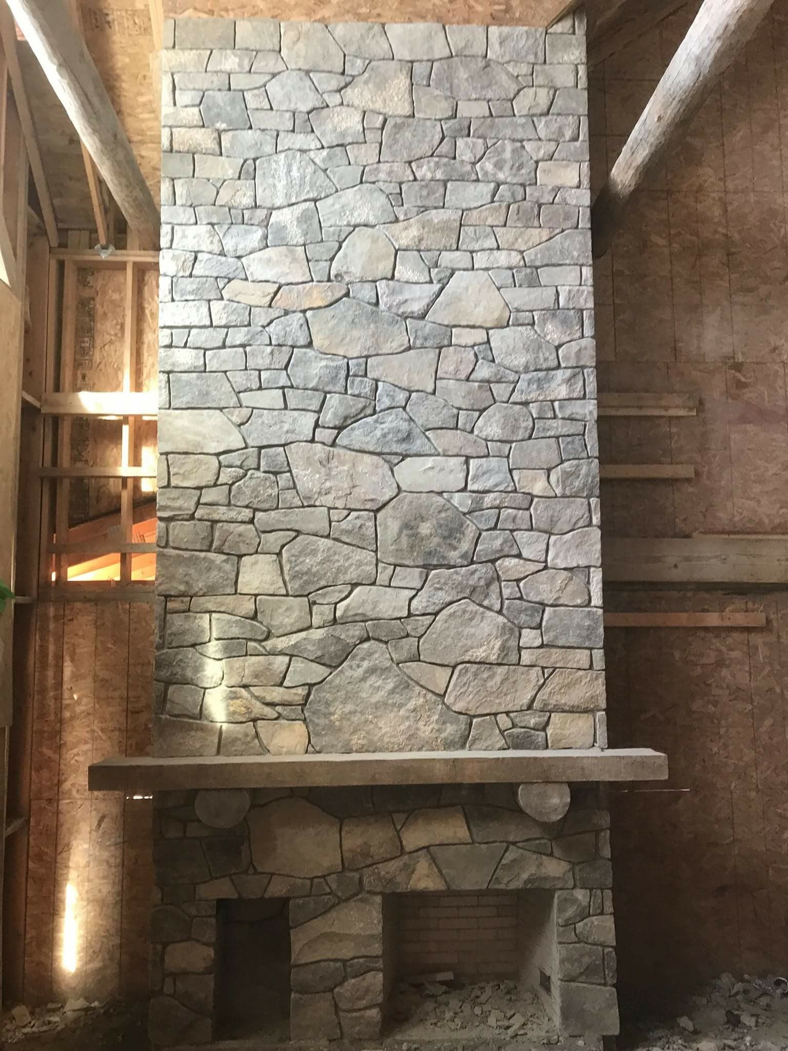 Stone fireplace in a rustic room with a tall chimney and wooden beams