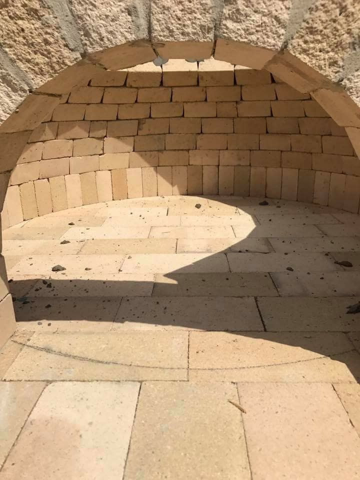 Stone alcove with curved brick wall and sunlit floor, forming a rounded shadow inside an arched niche