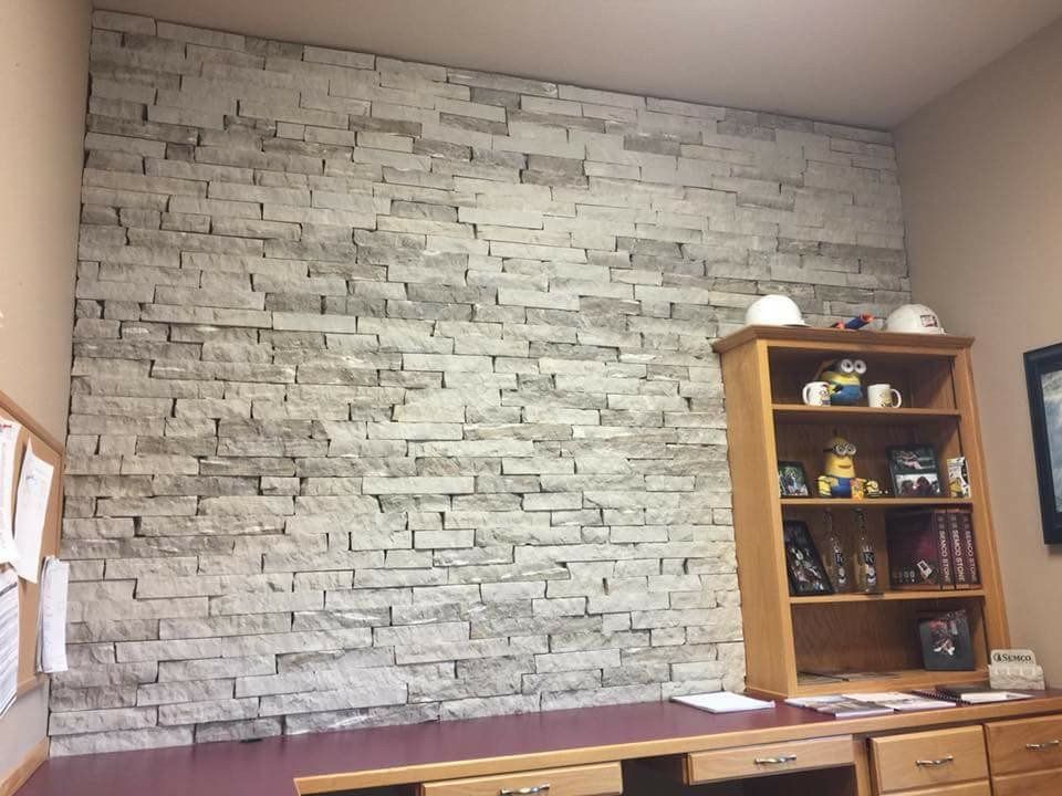 Room with a gray stone-pattern accent wall and wooden shelf on the right.