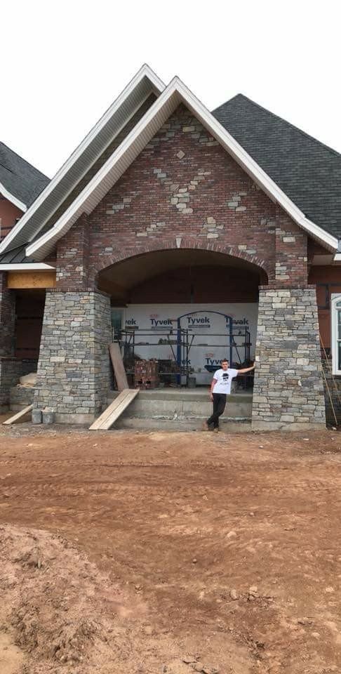 Brick house entrance with steep roof and a person standing on the dirt front yard